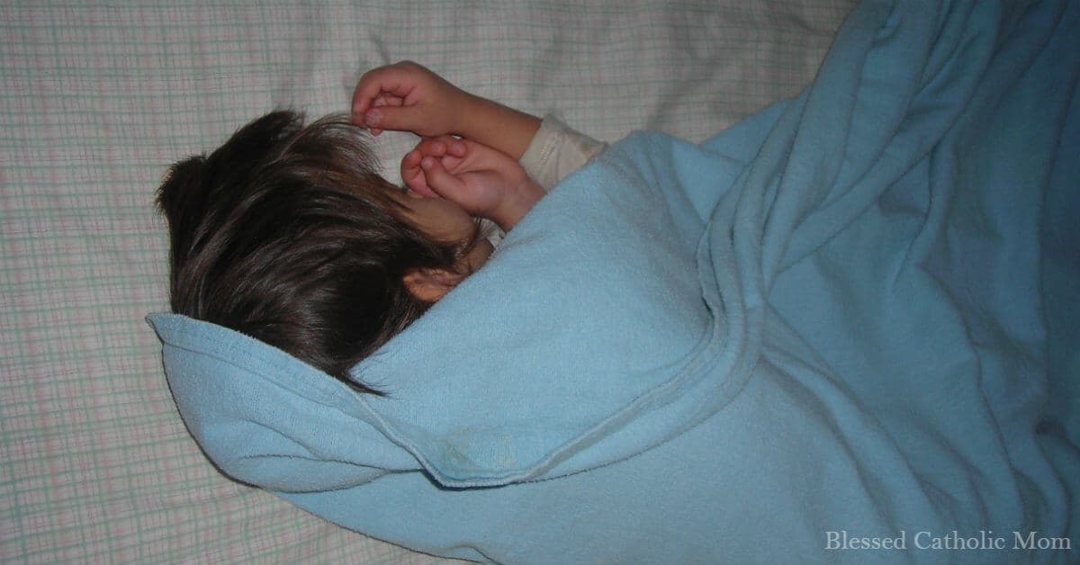 Get kids to bed earlier is easier when you follow these simple steps. Image of a little boy sleeping on his bed, covered by a light blue blanket.