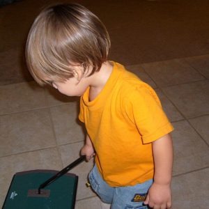 Having a routine to follow every night helps get kids to bed earlier. Image of a boy cleaning the floor with a push vacuum.