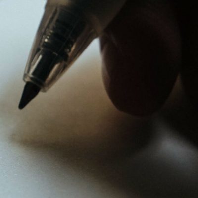 Follow Seven Steps to create Sanity Saving Routines. Image of a hand holding a pen over a blank sheet of paper. Image from Death to Stock Photo.