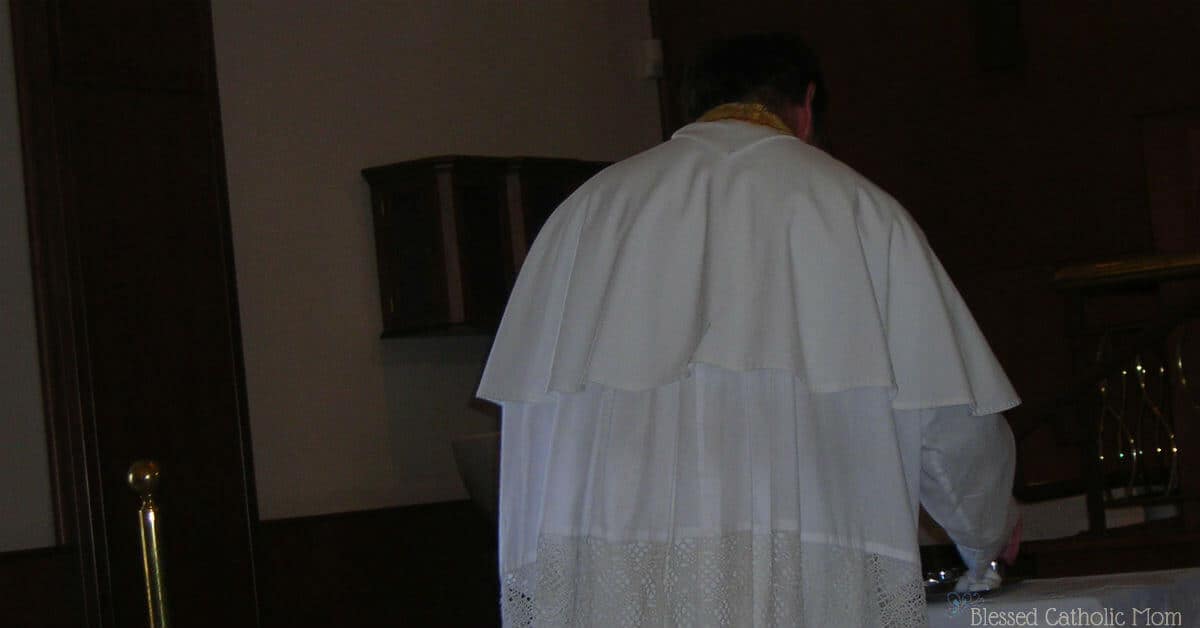 Image of a priest with his back to the camera as he is getting ready for a baptism. 