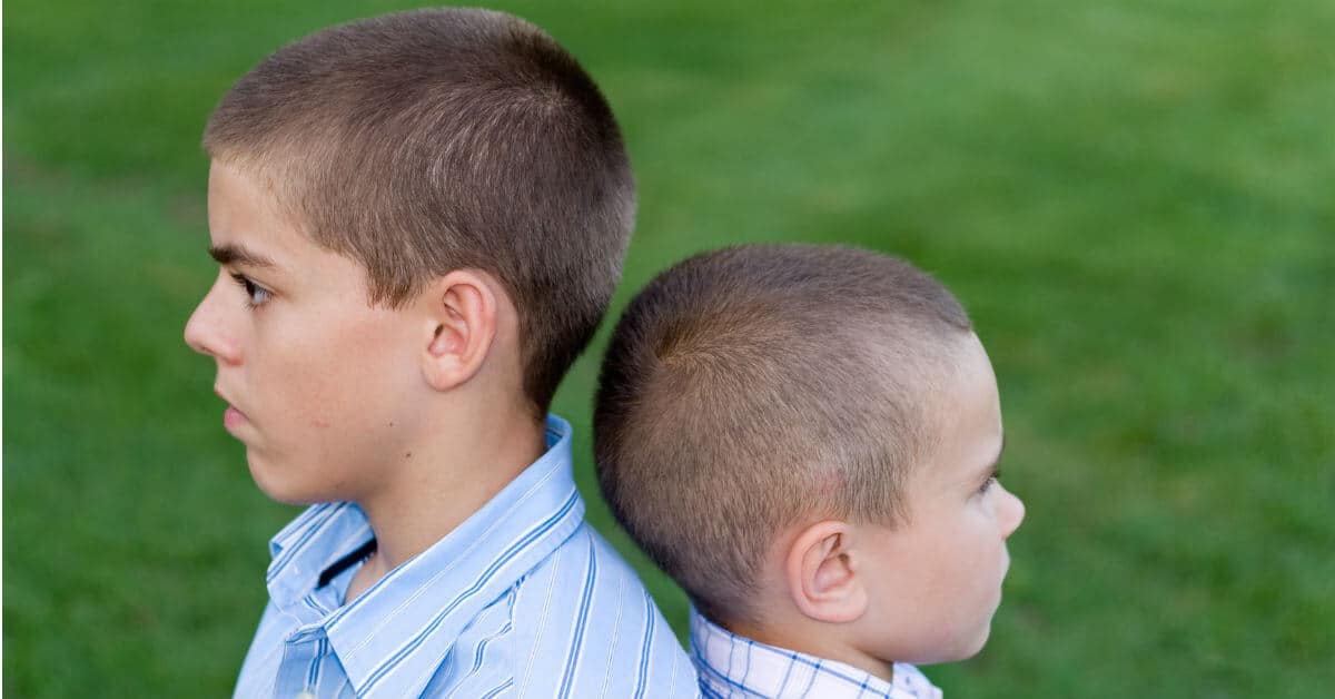 Parenting is on the job training. It is our job to help our kids learn to deal with their siblings as well as with others. Image of two boys back to back.