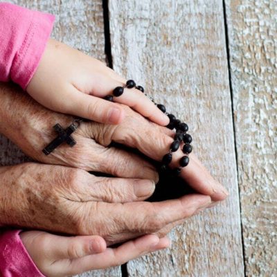 Do you want to start a family Rosary group? just follow these four simple steps. It is a fun and meaningful way for your family to pray the Rosary together. Image of two sets of hands together holding a Rosary.