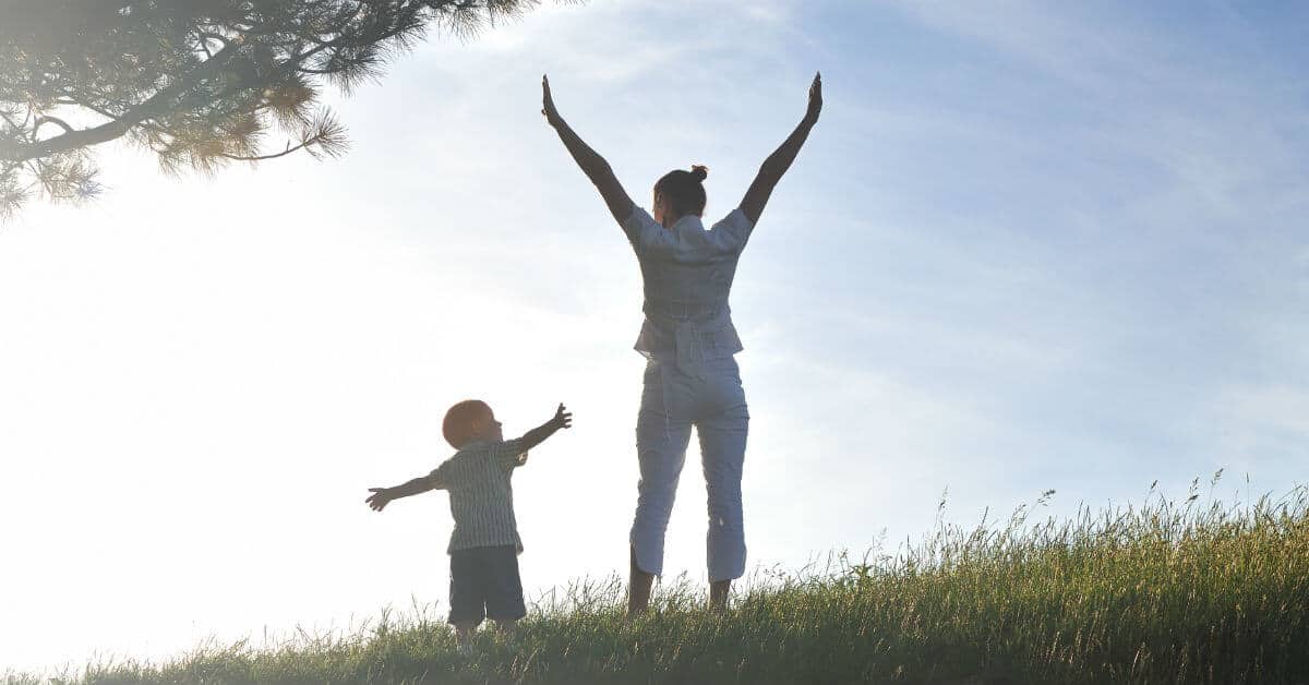 It can be challenging to live as God wants me to live on a daily basis. How do I know how God wants me to live each day? Ephesians, St. Paul tells us to live our vocation well. Image of woman and her son standing outside by a tree, facing the sun with their arms outstretched.