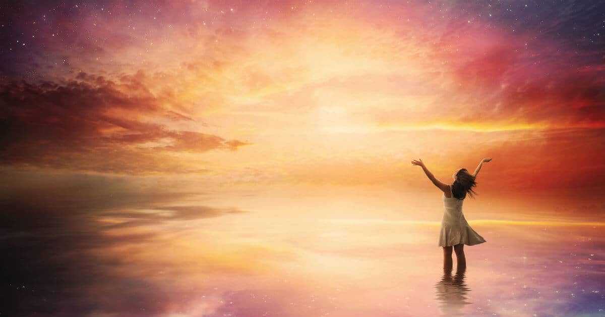 Image of a woman standing in praise before a beautiful night sky.