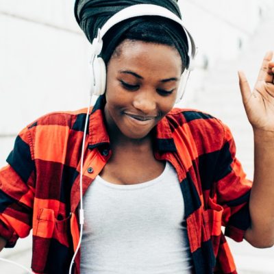 Image of a smiling woman listening to music while wearing headphones.