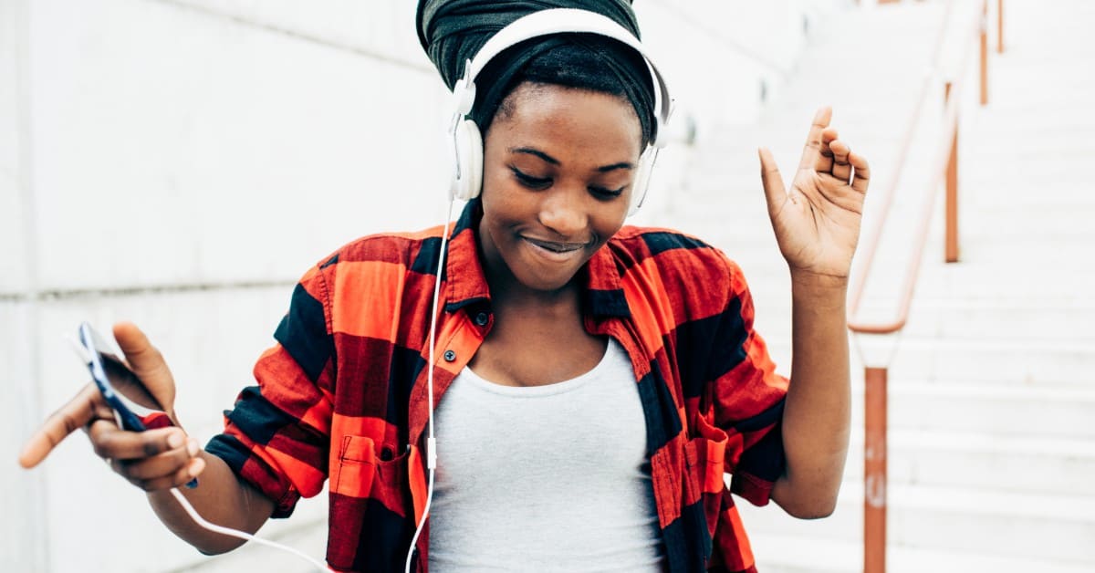 Image of a smiling woman listening to music while wearing headphones.