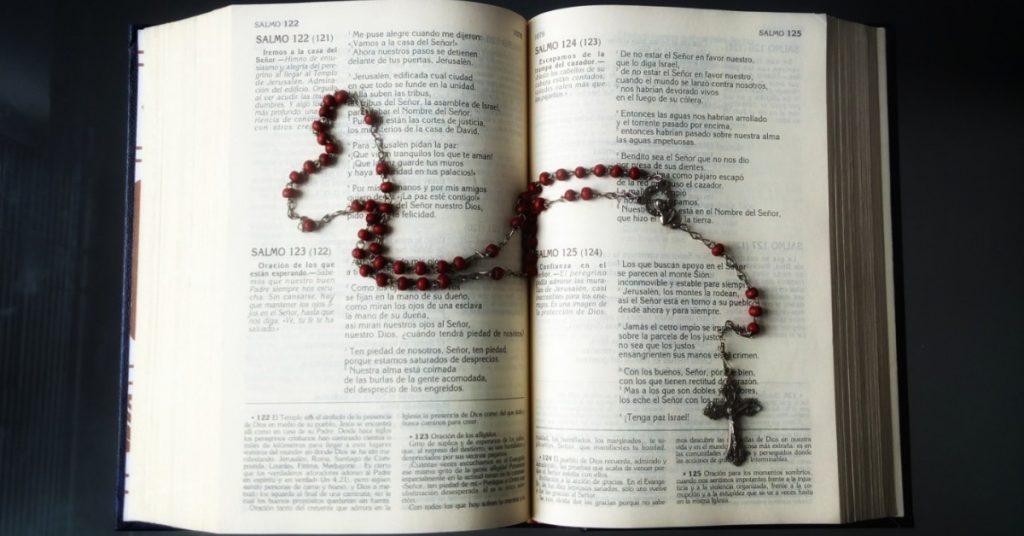 Image of a Rosary laid out on an open Bible with part of the Rosary in the shape of a heart.