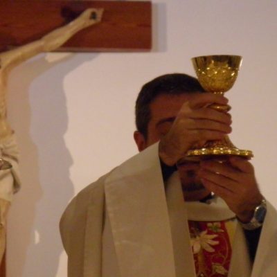Image of a priest at the altar holding the chalice with the Blood of Christ for the faithful to adore.