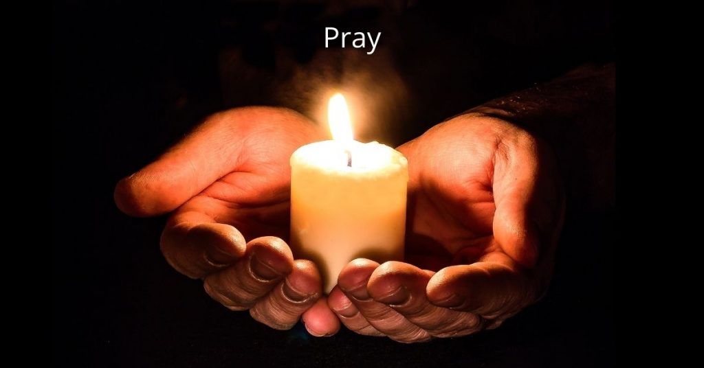 Image of two hands holding a lit candle. The word pray is above the image.