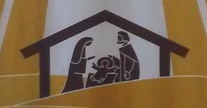 Image of a yellow and white banner with brown print showing the Holy Family at the nativity of Christ.